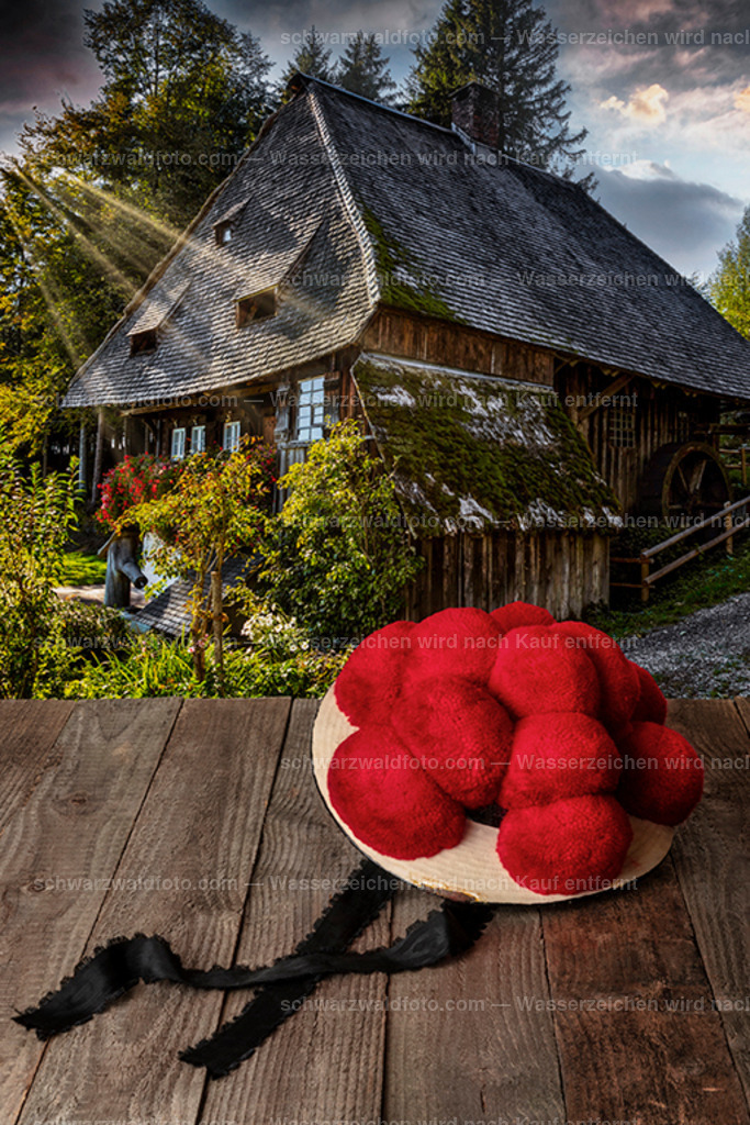 Schwarzwälder Bollenhut | Original Schwarzwälder Bollenhut auf Holztisch vor einer historischen Mühle - Realisiert mit Pictrs.com