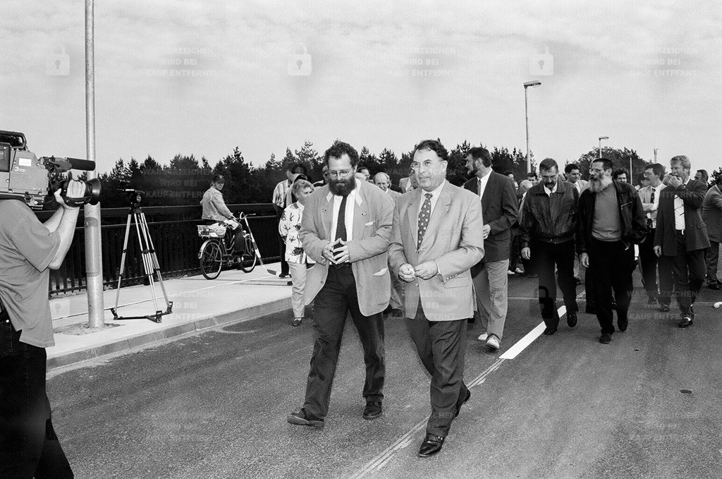 BD 0495_78 | 5.10.1995 - Europarc Kleinmachnow/Dreilinden. Öffnung der neuen Stahnsdorfer-Damm-Brücke  Festliche Öffnung der Stahnsdorfer-Damm-Brücke über die Autobahn A 115 als Verbindung zwischen Kleinmachnow und dem europarc in Dreilinden. Die Brücke hat eine Länge von 383 m und ist 6,50 m breit .   Lucien Triponel, Geschäftsführer Europarc.  Wolfgang Blasig, Bürgermeister.   Der Europarc Dreilinden ist ein Gewerbepark, der, beginnend mit dem Ersten Spatenstich am 3.12.1993, auf dem Gelände des ehemals europaweit größten Grenzkontrollpunkts Drewitz entstanden ist. Die gesamte Fläche des Gewerbeparks beläuft sich auf 450.000 Quadratmeter. Der Park ist mit seinen 70 Vogelarten, über 300 verschiedenen Pflanzen und Schmetterlingsarten, die sich hier in unberührter Natur entwickeln können, Bestandteil eines großen Naturschutzgebietes.Im März 1995 beginnen die ersten Arbeiten auf dem Gelände. Es müssen 24 ha versiegelte Betonfläche recycelt werden. Am 31.01.1996 erhalten die Straßen auf dem Gelände Namen nach prominenten Physikern. Im März des Jahres kann das erste Bürogebäude bezogen werden. Am 21.02.2001 eröffnet das Hotel "Ibis" mit 81 Zimmern. Im April 2002 eröffnet das Hotel "Motel one"mit 105 Doppelzimmern.Am 22.09.1997 beginnt der Abriss der ehemaligen Dienst- und Verwaltungsgebäude der DDR-Zollverwaltung auf der Kleinmachnower Seite der Autobahn (dem Europarc gegenüber). Nach der Wende bis zum Abriss wurden die Gebäude durch die BRD-Zollfahndung genutzt, die am 19.06.1997 nach Teltow zog. - Realisiert mit Pictrs.com